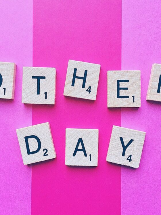 Gifts Your Mom Will Love: Mother's Day spelled out in Scrabble Tiles against a pink striped background
