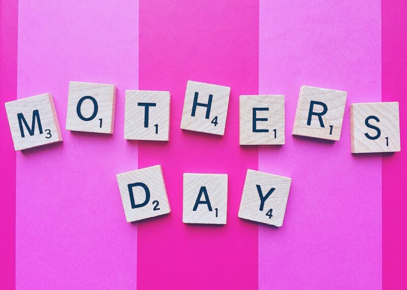 Gifts Your Mom Will Love: Mother's Day spelled out in Scrabble Tiles against a pink striped background