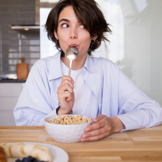 Healthy Snacks: Woman licking her spoon in front of a cereal bowl