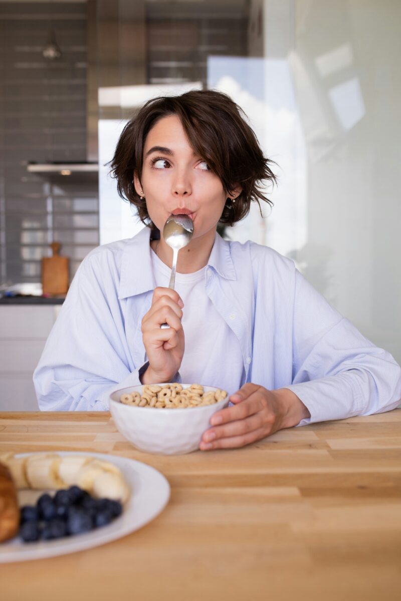 Healthy Snacks: Woman licking her spoon in front of a cereal bowl
