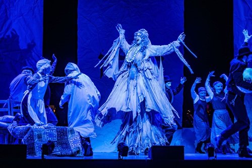 Fiddler On The Roof In Yiddish: Scene from the musical with actross floating in mid-air over actors in a bed