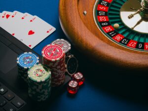 Online Gambling: Roulette wheel, poker chips and playing cards near a laptop
