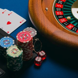 Online Gambling: Roulette wheel, poker chips and playing cards near a laptop