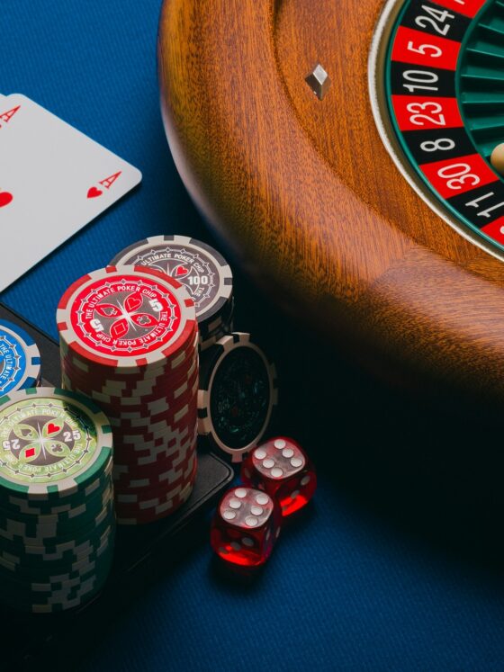 Online Gambling: Roulette wheel, poker chips and playing cards near a laptop