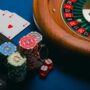Online Gambling: Roulette wheel, poker chips and playing cards near a laptop
