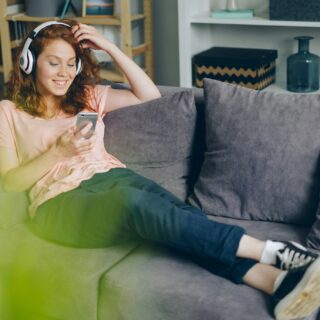 Entertainment Apps: woman on her couch with headphones and her cell phone