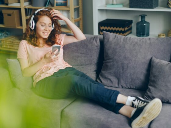 Entertainment Apps: woman on her couch with headphones and her cell phone
