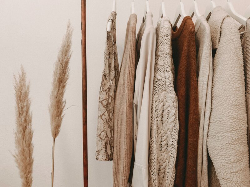Minimalist Fall Wardrobes: Tops and sweaters hanging on a clothing rack