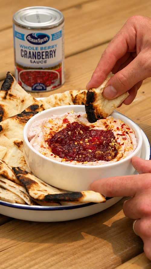 Cranberry Sauce: Person dipping pita into whipped feta and cranberry dip