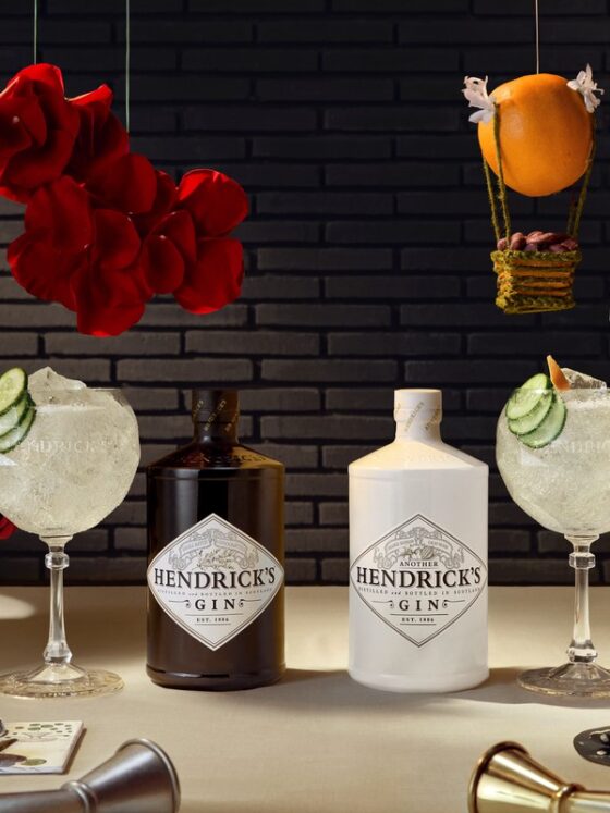 Hendrick's: Two bottles of Hendrick's Gin - one white and one black each with a cocktail beside it and cucumber, roses and an orange in the background