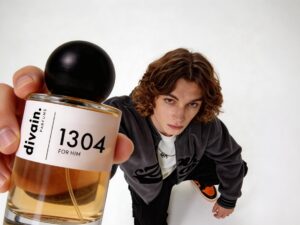 Perfume Dupes: Man with long hair holding a bottle of divain. 1304
