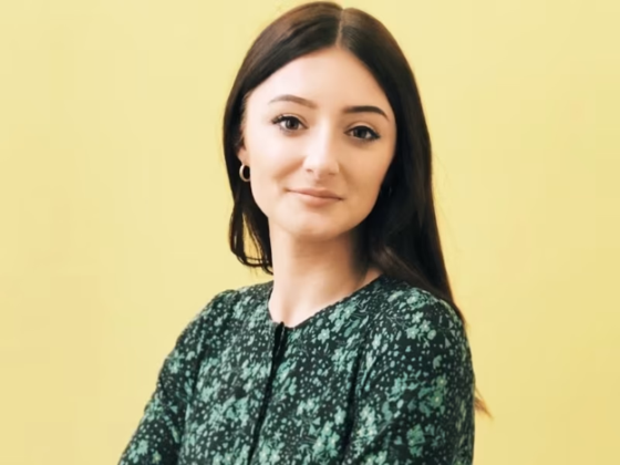 iGaming Expert: Young Woman with long brown hair wearing a green top against a pale yellow background