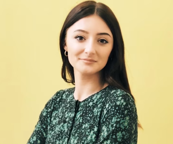 iGaming Expert: Young Woman with long brown hair wearing a green top against a pale yellow background