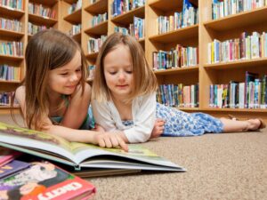 Best Kids' Books: two little girls in front of a pile of books at the library