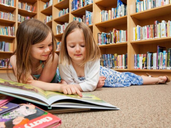 Best Kids' Books: two little girls in front of a pile of books at the library