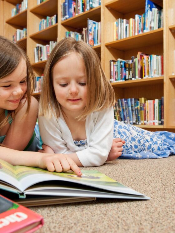 Best Kids' Books: two little girls in front of a pile of books at the library