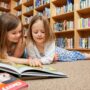 Best Kids' Books: two little girls in front of a pile of books at the library