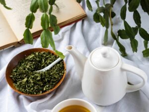 Green Tea Extract: Tea pot next to tea cup with green tea, loose leaves in a bowl next to a plant