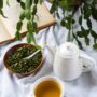 Green Tea Extract: Tea pot next to tea cup with green tea, loose leaves in a bowl next to a plant