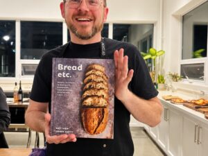 Sourdough: Matthew James Duffy in a commercial kitchen holding a copy of his cookbook, Bread, etc.