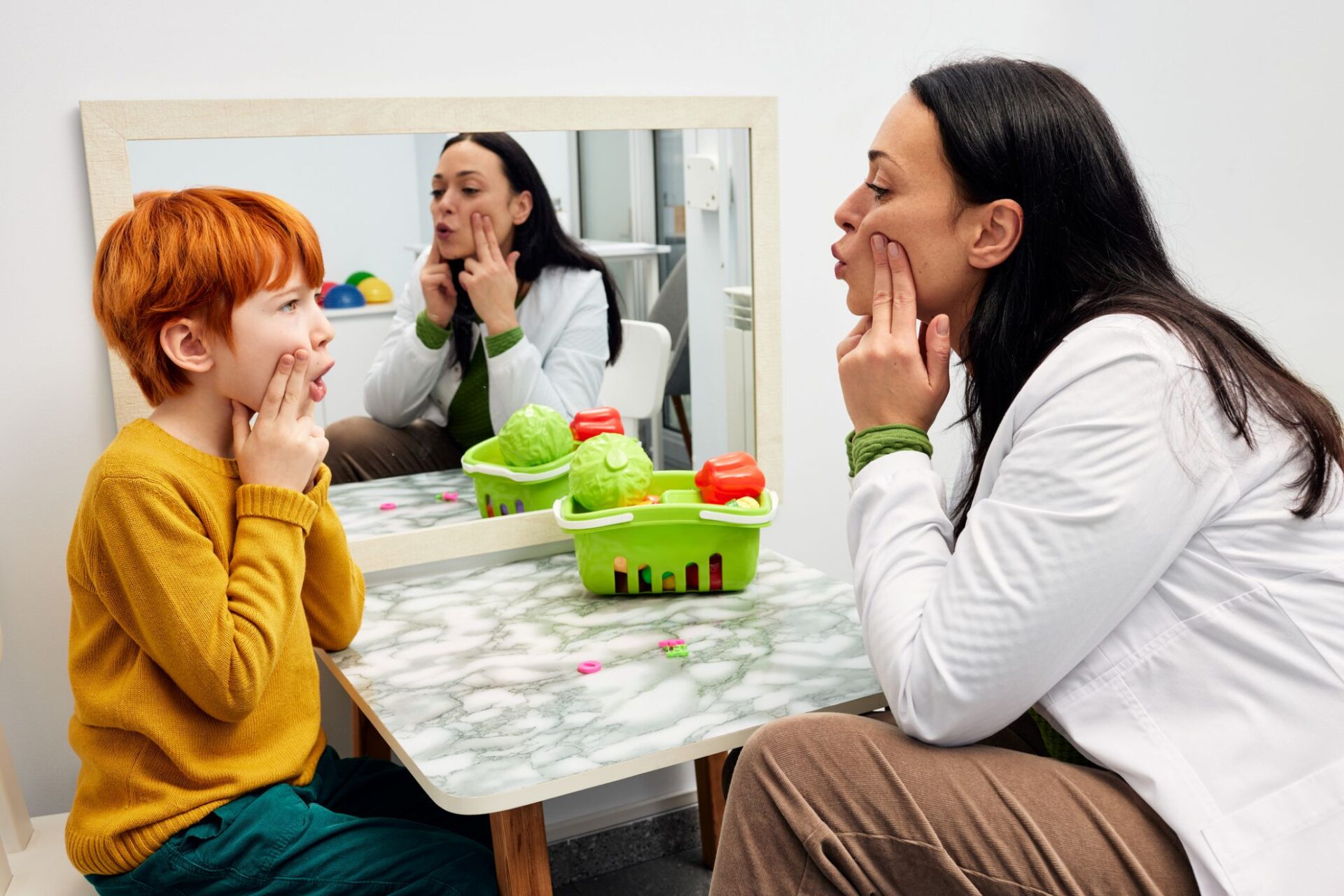 Stutter: female speech pathologist working with a young red-headed boy
