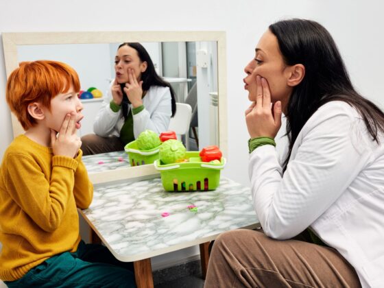 Stutter: female speech pathologist working with a young red-headed boy
