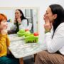 Stutter: female speech pathologist working with a young red-headed boy