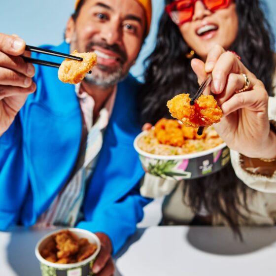 Calamari: Couple holding Thai Express Bowls with food on chopsticks