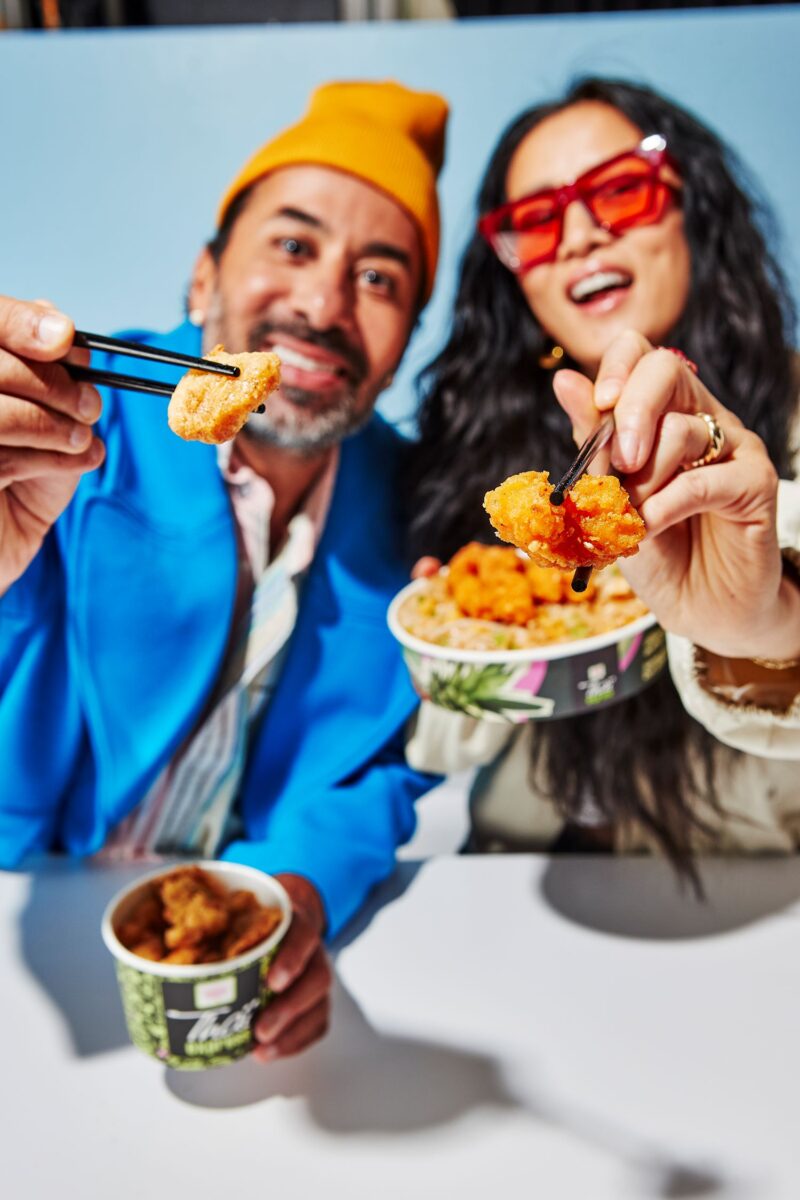 Calamari: Couple holding Thai Express Bowls with food on chopsticks