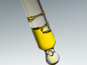 Compte-gouttes de verre laissant couler un sérum doré