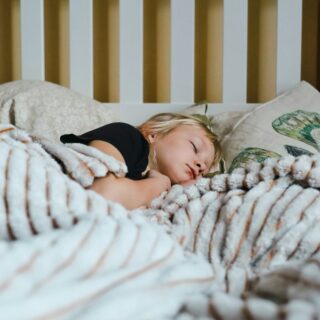 Petite fille qui dort paisiblement dans un lit sous une couverture