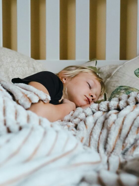 Petite fille qui dort paisiblement dans un lit sous une couverture
