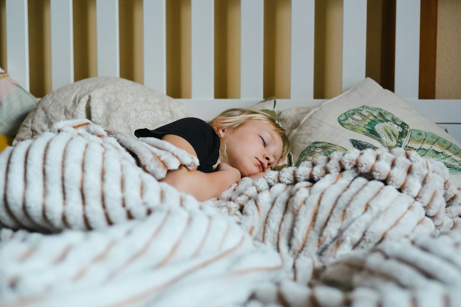 Petite fille qui dort paisiblement dans un lit sous une couverture