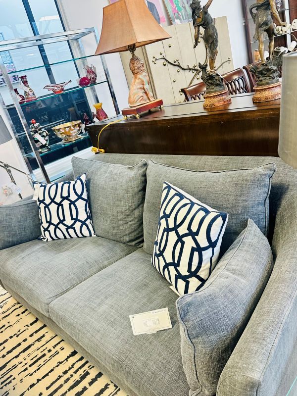 Shop Consignment: Contemporary gray couch with abstract throw pillows and antiques in the background
