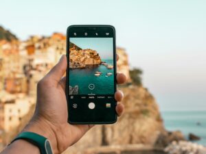 Main tenant un téléphone intelligent pour photographier une côte et la mer